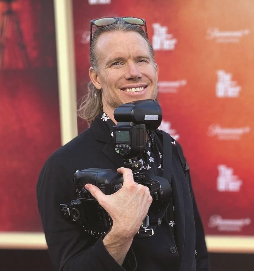 Man on red carpet holding camera