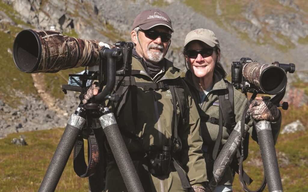 Two people in camouflage with large cameras